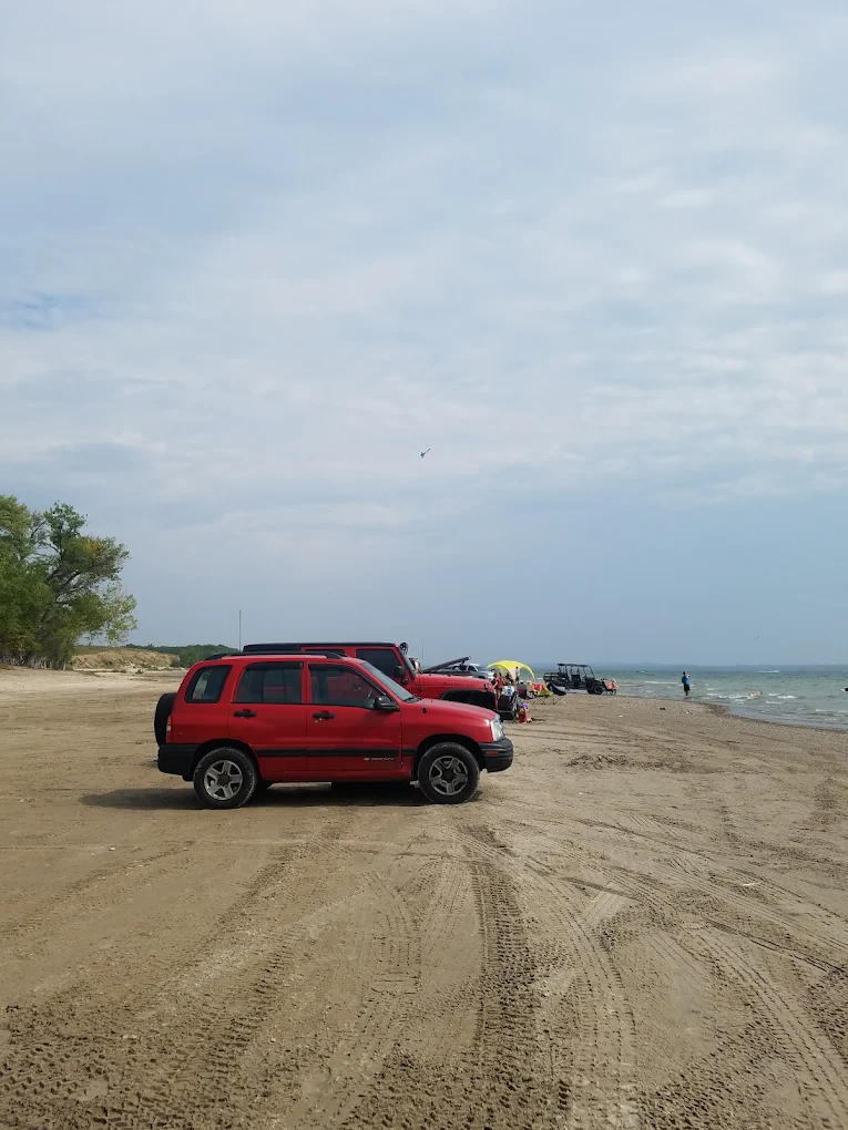 Vehicles parked on the wide sandy north shore — drive on, set up camp